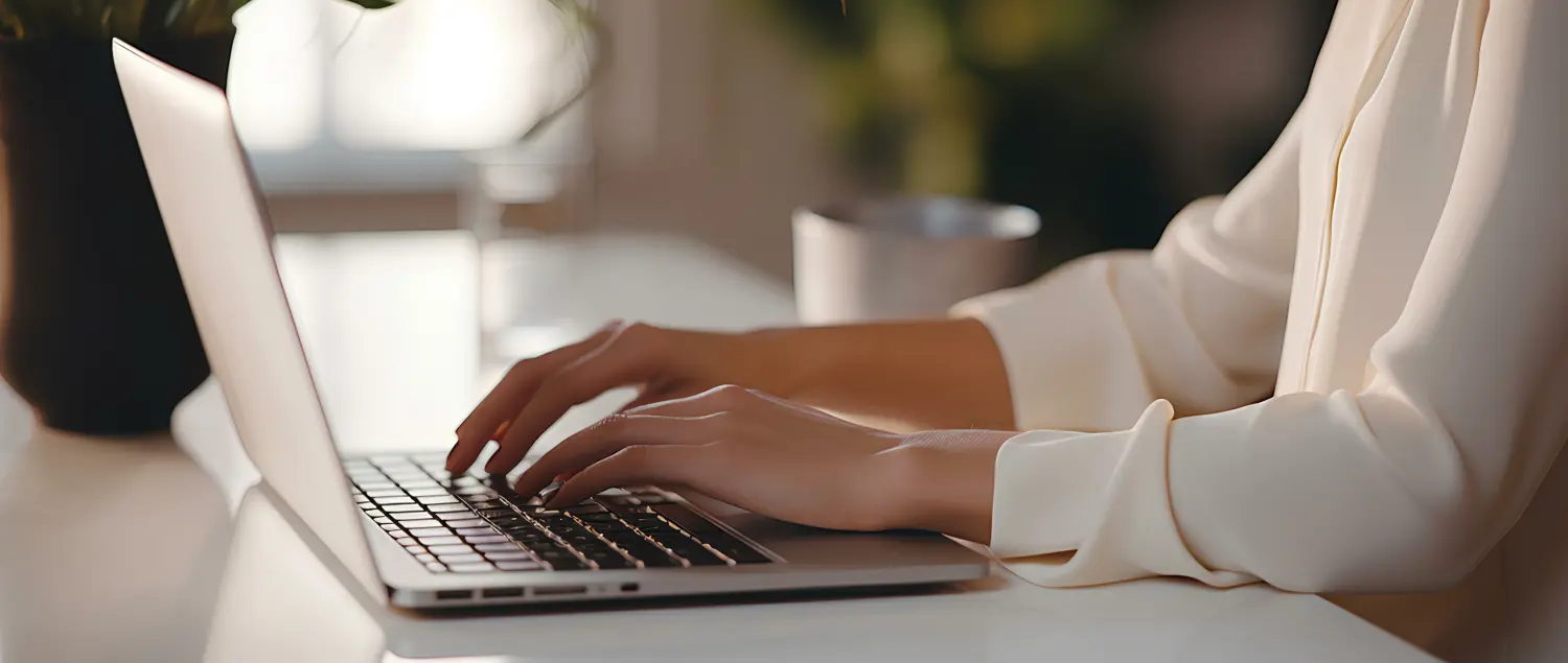 Frau tippt und benutzt ihren Laptop auf dem Tisch im Büro